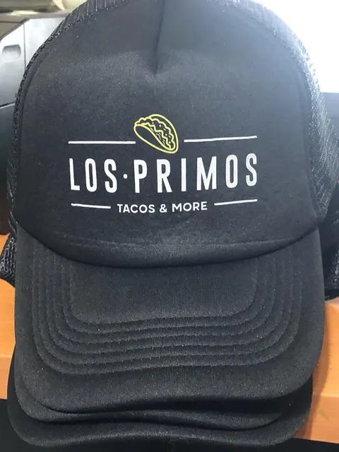 Gorra trucker negra con el logo de Los Primos Tacos & More